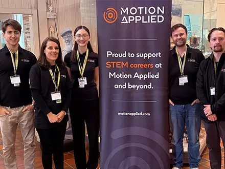 Five people stood in front of a Motion Applied banner at Brooklands STEM event