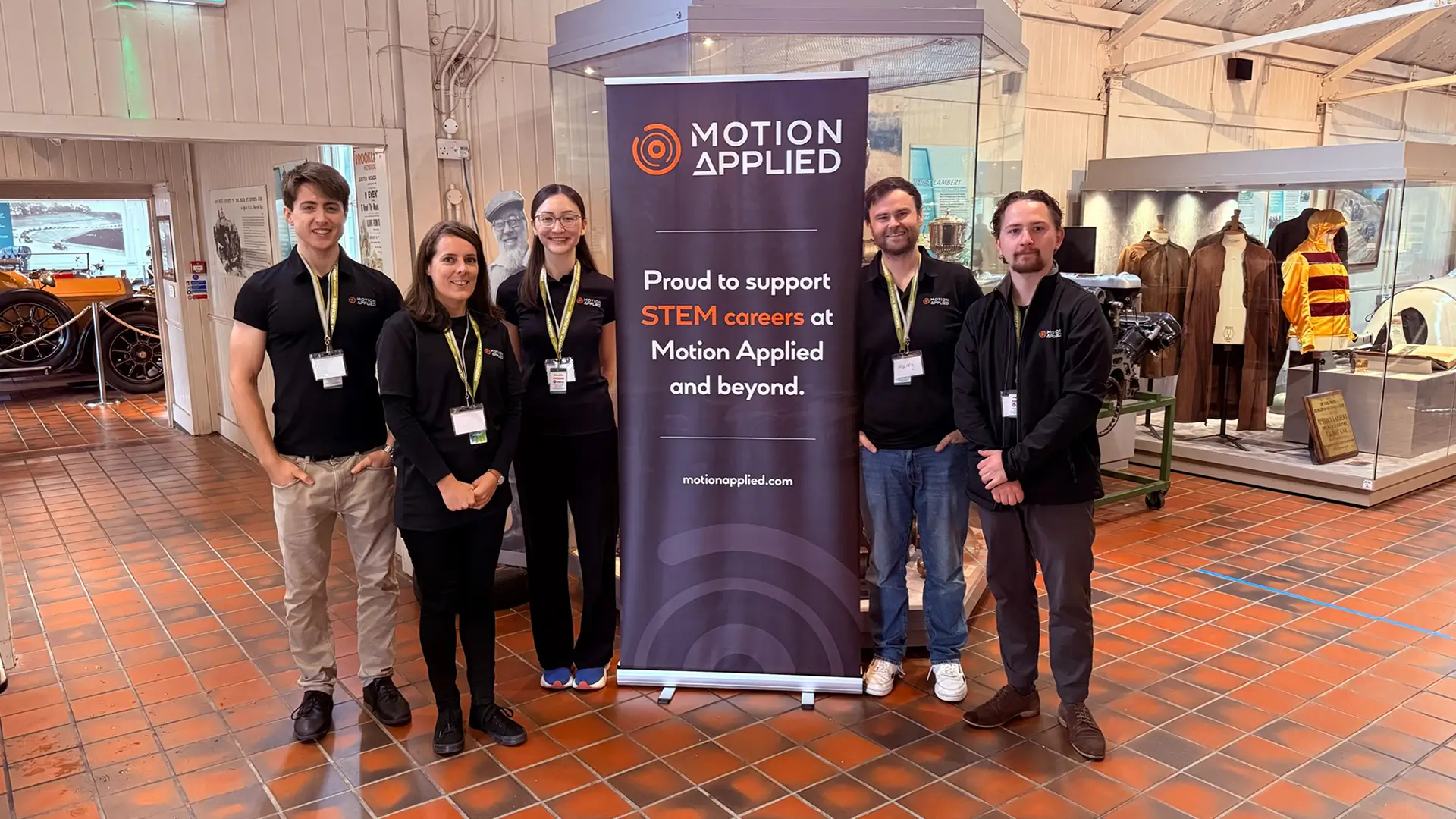 Five people stood facing the camera in front of a Motion Applied branded STEM banner